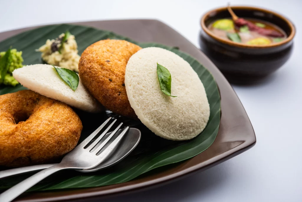 Idli and medu vada served with sambar and chutney on banana leaf South Indian catering dish
